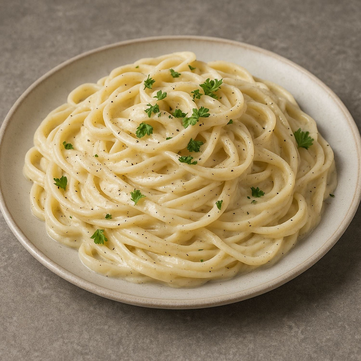 Fettuccine Alfredo mit cremiger Sahnesauce, frischem Parmesankäse, SPINTZ Weißem Pfeffer und Petersilie, perfekt angerichtet auf einem Teller.