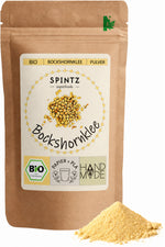 SPINTZ Bio-Bockshornklee-Pulver im Kraftpapierbeutel mit fein gemahlenem, gelbem Pulver im Vordergrund.