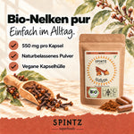 SPINTZ Bio-Nelken-Kapseln mit naturbelassenem Nelkenpulver und veganer Kapselhülle neben ganzen Gewürznelken.