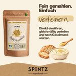 SPINTZ Bio-Bockshornklee als Gewürz für Currys, Dal und Gemüsegerichte, neben einer Schale Curry.